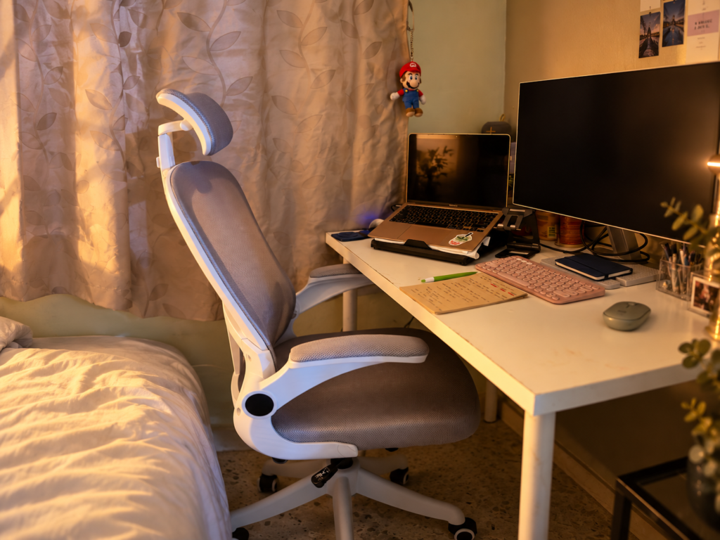 Cozy home workspace with laptop, monitor, keyboard and desk setup in warm lighting